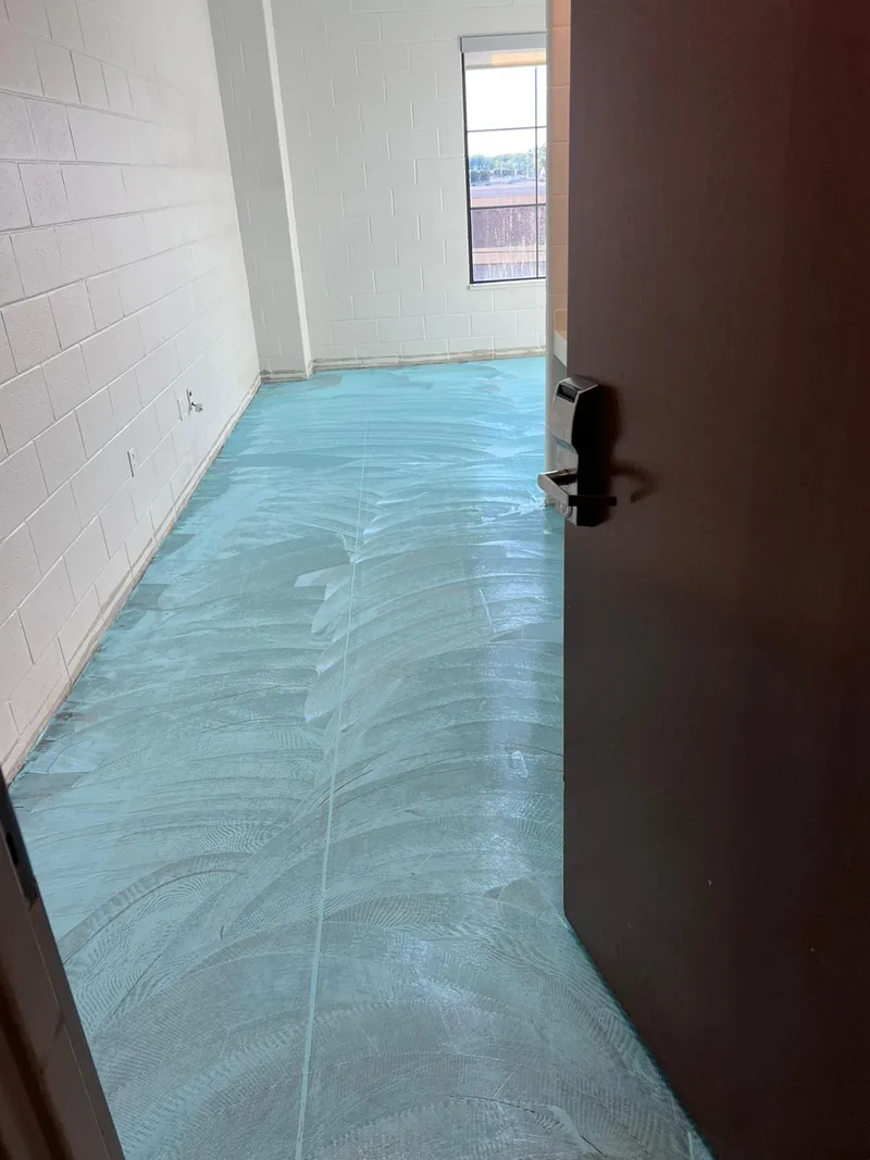 Blue coating troweled across the slab of a room before the floor went down