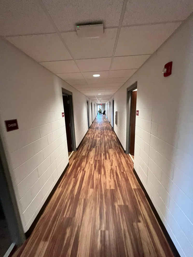 Long dormitory corridor with installed brown-toned flooring and doors on both sides