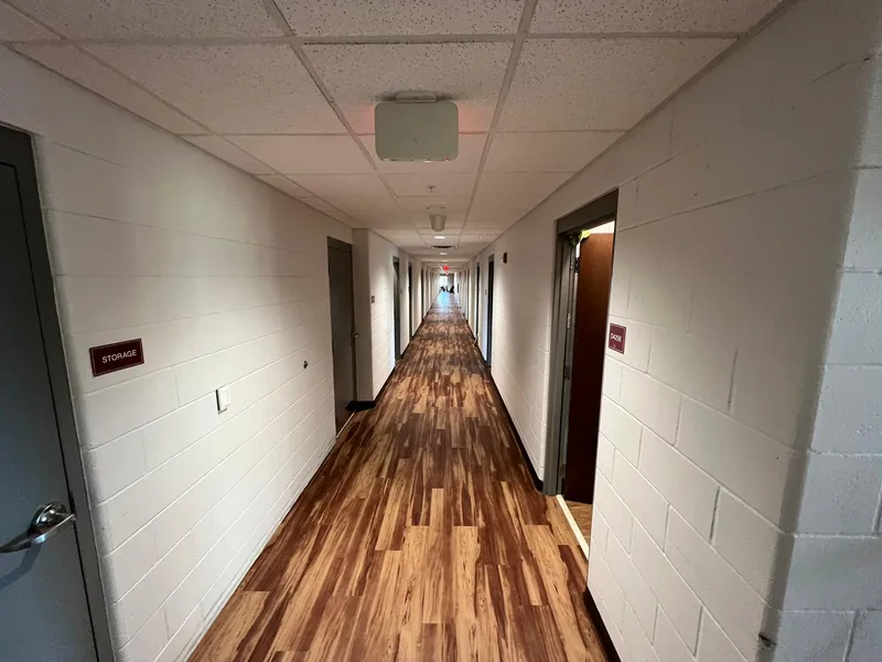 Long finished corridor with the flooring running straight to the far end, doors on both sides