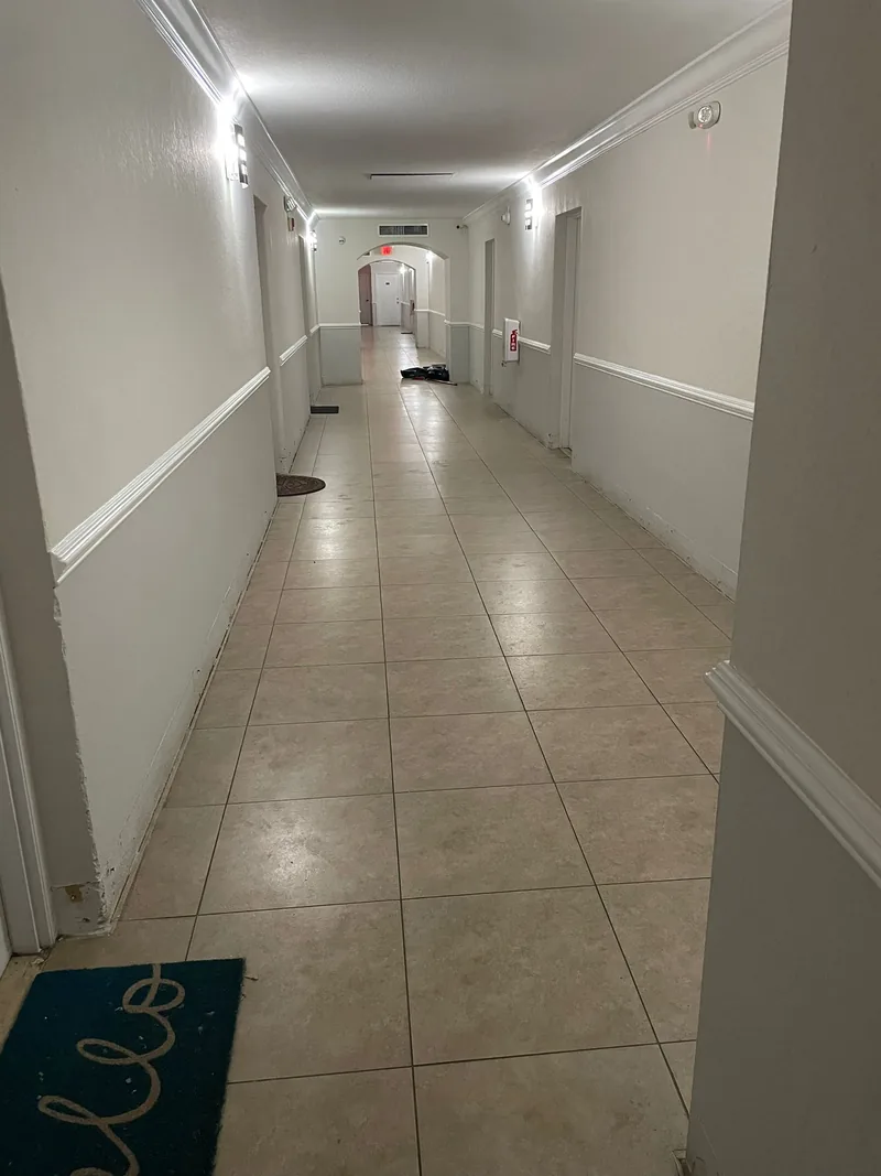Corridor stretch still on its original tile floor, photographed the same day the adjacent stretch was opened