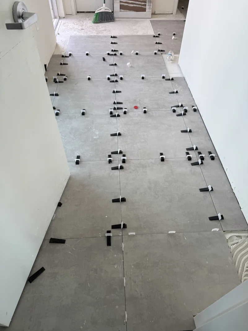 Leveling clips holding adjacent planks flush across a floor under installation
