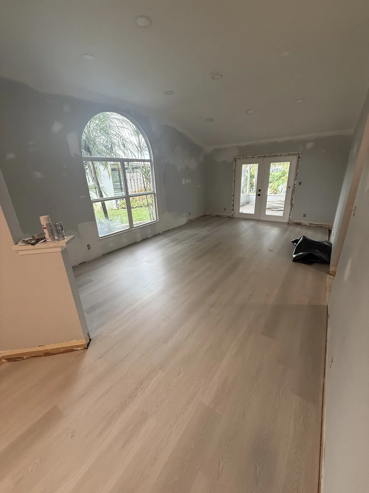 Finished Misty Meadows room with light flooring and an arched window